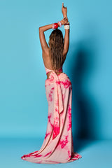 back view of a woman in a light pink and magenta tie-dye maxi dress with an open back and tie detail