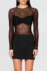 woman wearing a black sheer long-sleeve top with a ruched sweetheart bodice and a ruched mini skirt