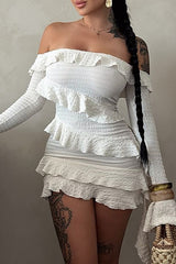 Woman wearing a white off-the-shoulder mini dress with long sleeves and ruffled trim.