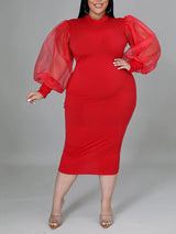 Plus-size woman wearing a red mock neck sheath dress with sheer puff sleeves and a slit hem, front view