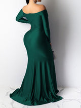 Back view of a woman in a green off-the-shoulder long-sleeved mermaid gown with a high slit