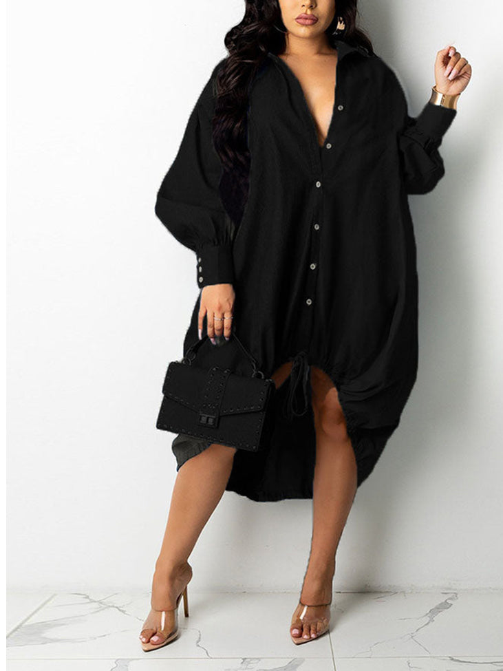 Woman wearing a black oversized shirt dress with button-down front and adjustable drawstring hem, holding a black handbag.