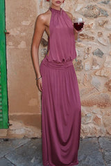 woman wearing a plum halter neck maxi dress holding a glass of red wine