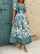 Full body shot of a woman in a white and green floral print midi dress.