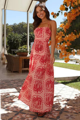 Woman wearing a pink maxi dress with a red palm tree print and halter neckline