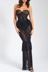 Woman wearing a black lace strapless gown with a peplum waist and tiered fishtail hem, front view