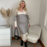 Plus-size woman wearing a long-sleeved striped maxi dress, black boots, and a black handbag
