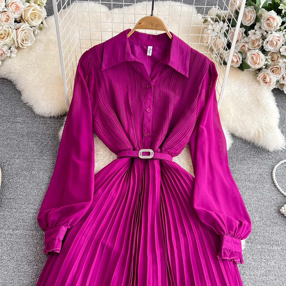 Close-up of a magenta pleated midi dress, showing the button-up bodice and belted waist.