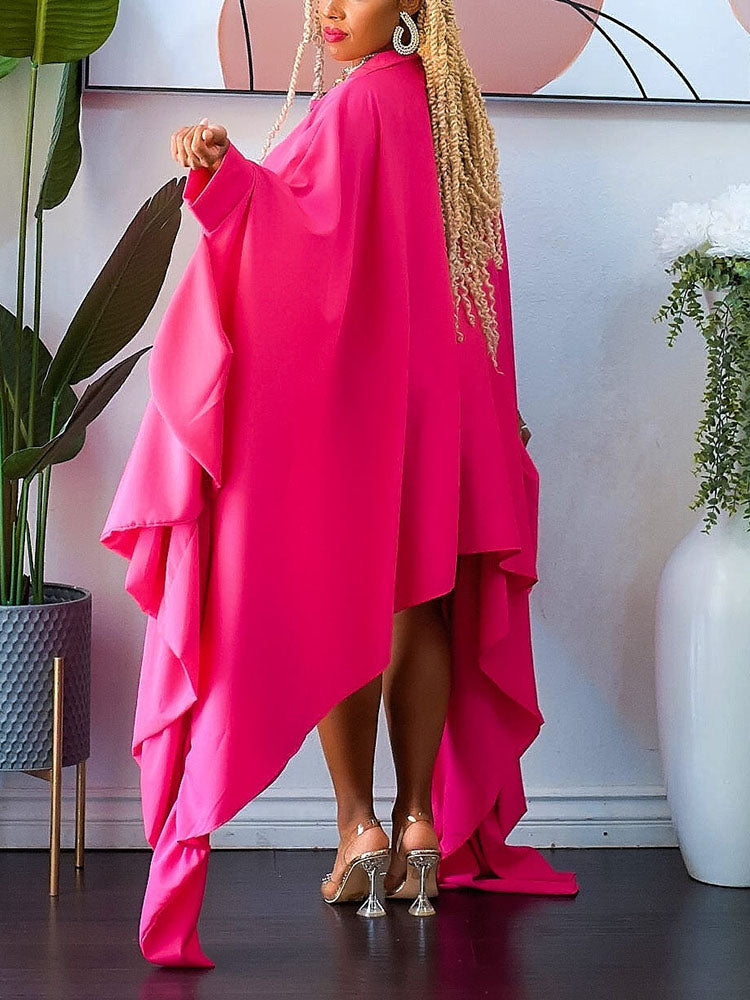 Back view of a woman in a voluminous pink shirt dress with a high-low hemline and dramatic draped detailing.