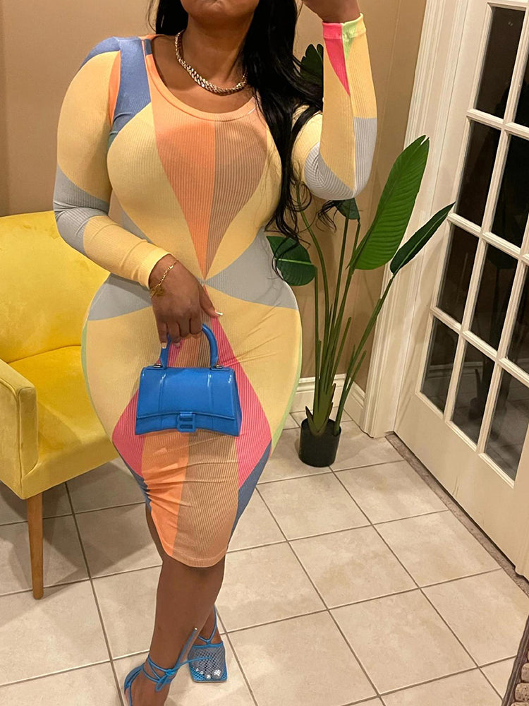 Woman wearing a long-sleeved, midi-length bodycon dress with a geometric pattern in pastel tones, accessorized with blue strappy heels and a blue handbag.