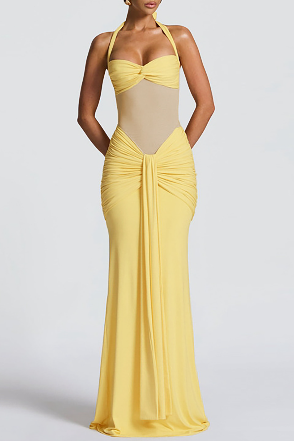 Woman wearing a floor-length yellow halter dress with ruched detailing and a sheer bodice, front view