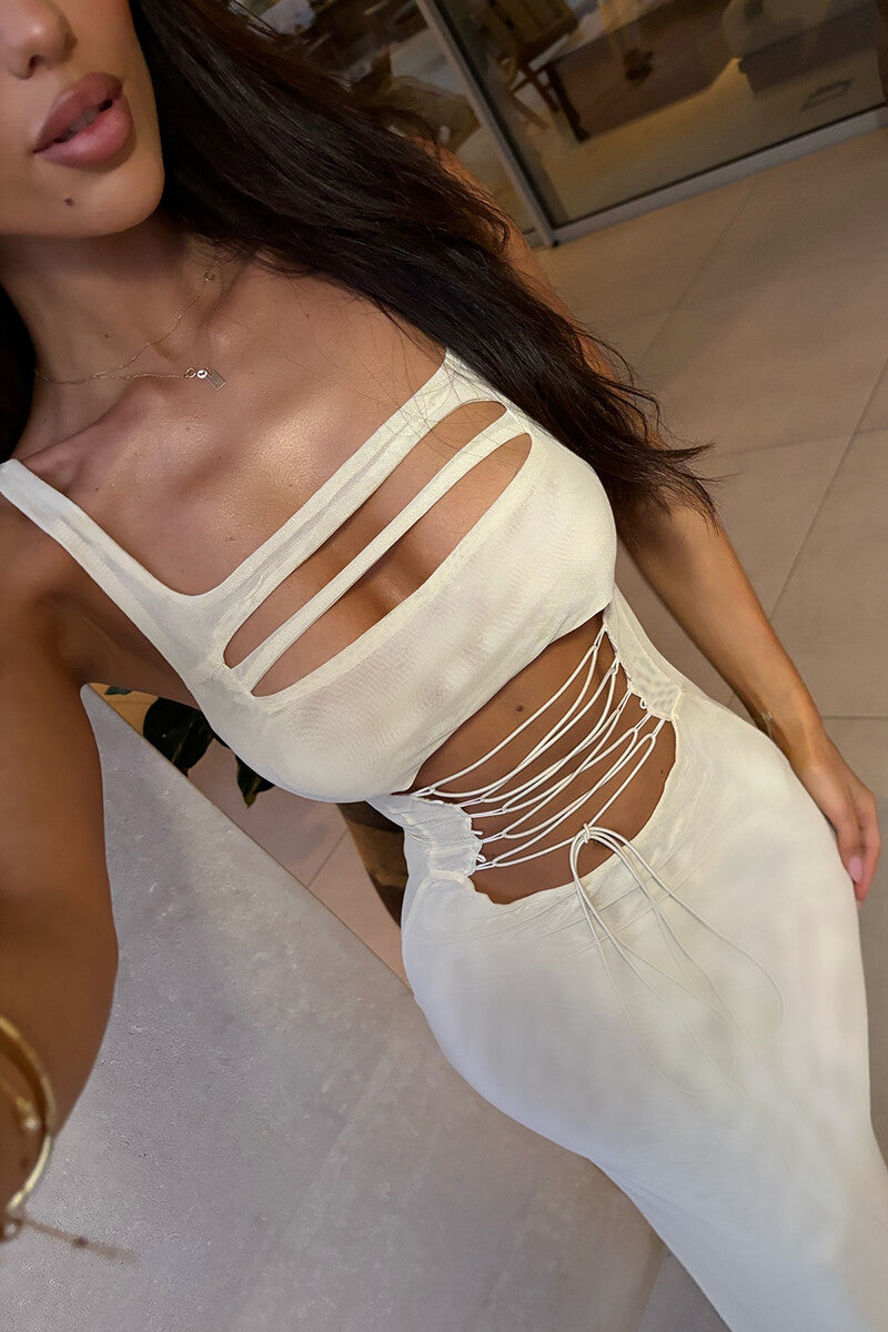 Close-up of the chest and waist area of a white maxi dress with intricate cut-out and lace-up details.