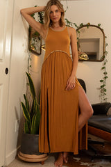 Woman wearing a sleeveless rust-colored maxi dress with high leg slits and a lace-trimmed neckline, standing with her hand on her hip.
