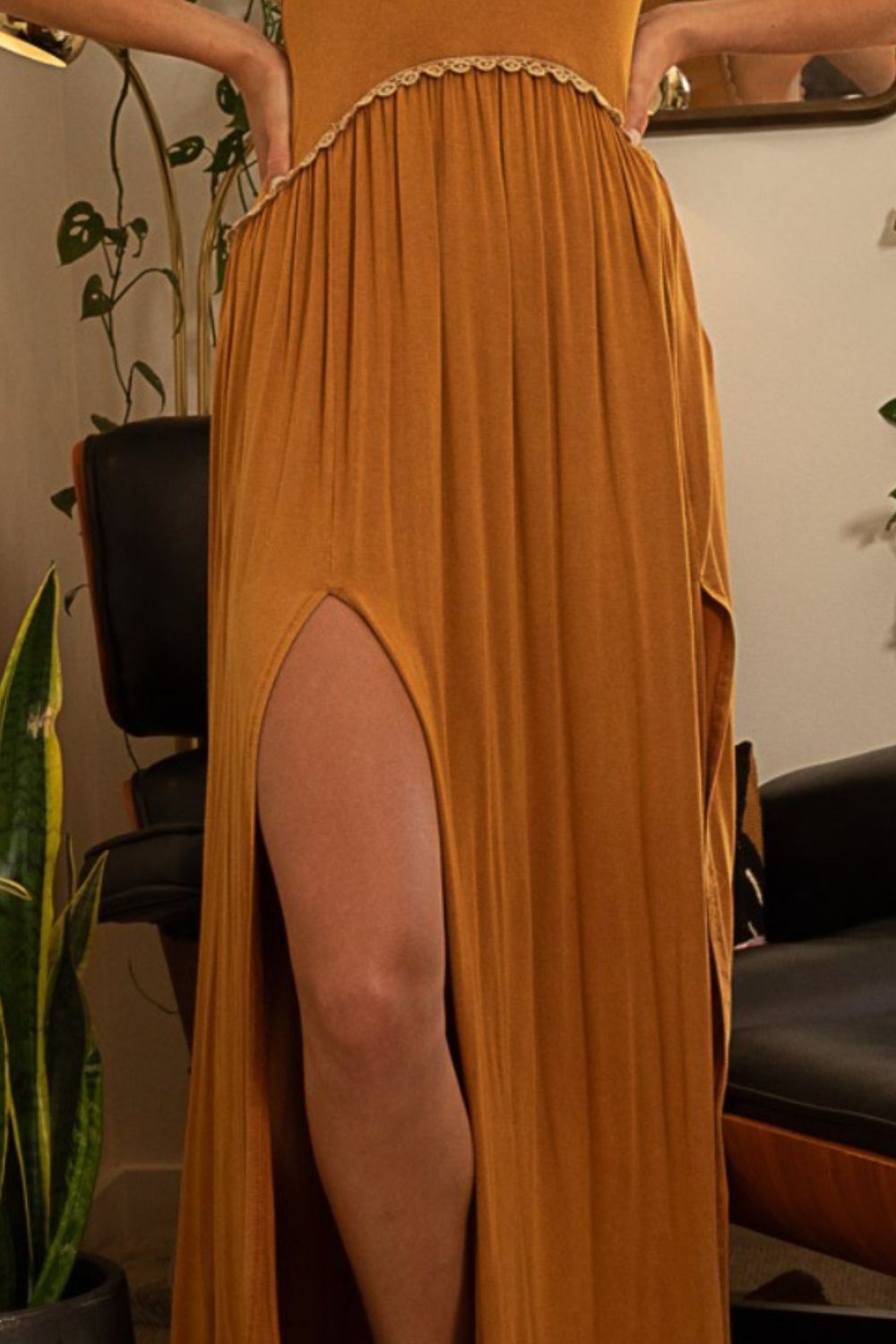 Close-up of the high leg slit on a rust-colored maxi dress worn by a woman.