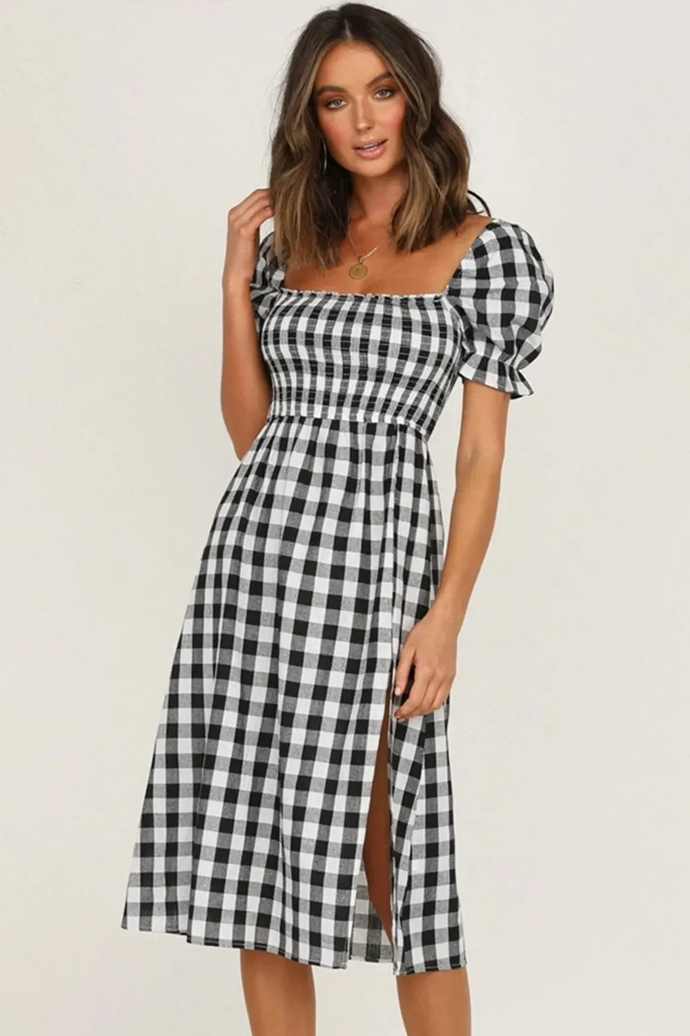 Front view of a woman wearing a black and white gingham check midi dress with puff sleeves and a square neckline.