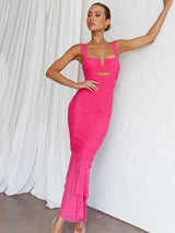 Woman wearing a bright pink ruched mesh gown with a cutout detail and ruffled hem, posing against a white backdrop.