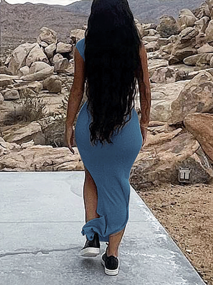 Rear view of a woman wearing a blue one-shoulder, draped maxi dress with a high slit and sneakers, walking away.