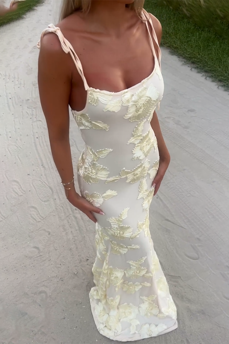 Full body shot of a woman wearing a cream floral appliqué evening gown with tie shoulder straps.