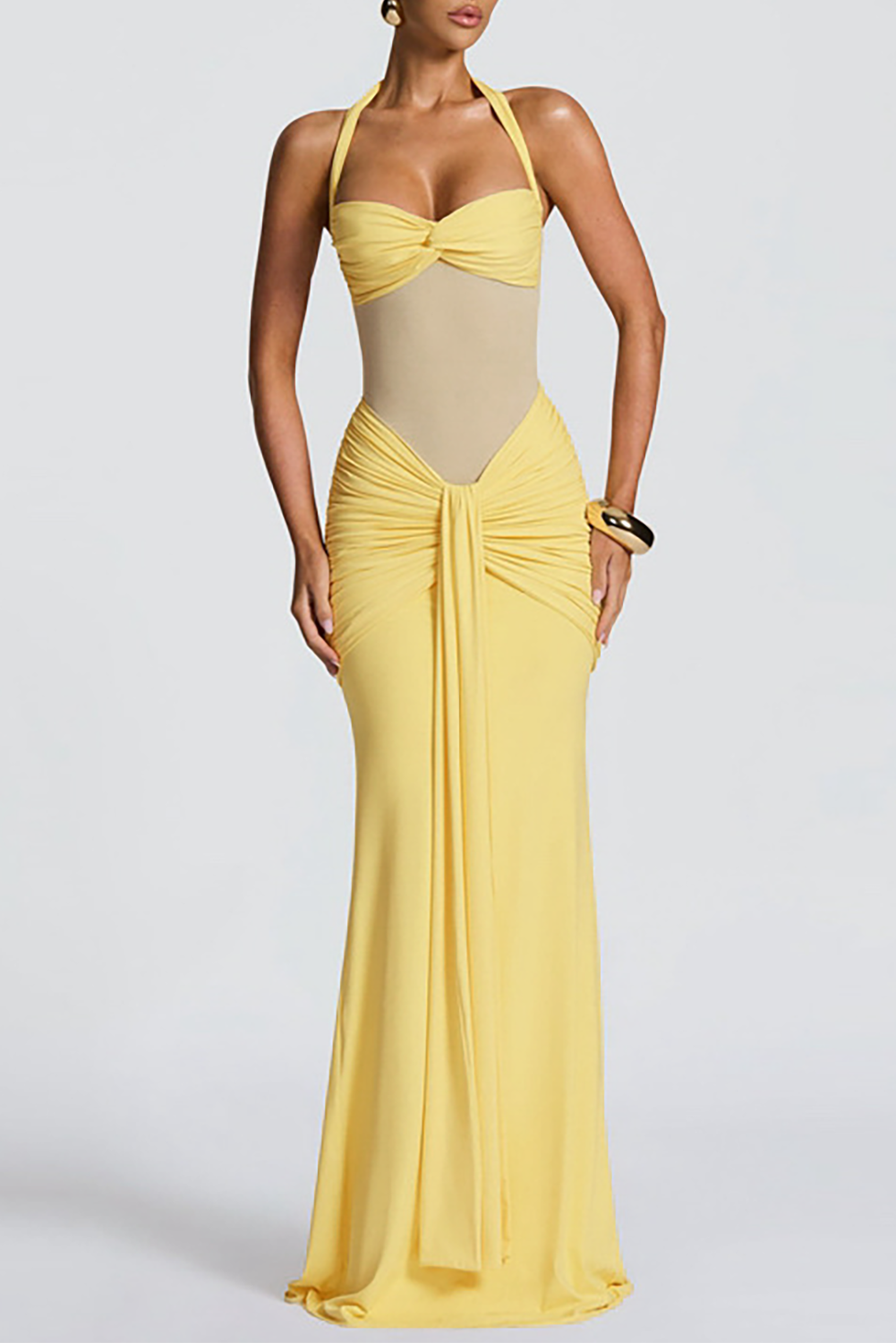 Woman wearing a floor-length yellow halter dress with ruched detailing and a sheer bodice, front view