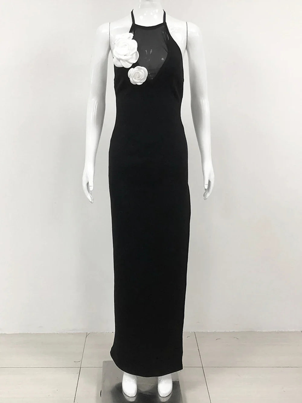 black floor-length halter dress with white floral embellishments displayed on a mannequin
