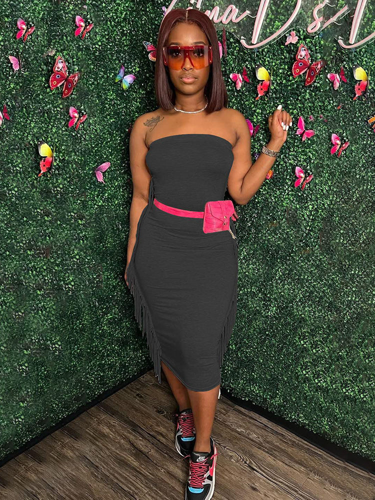 Woman wearing a black strapless midi dress with fringe trim and a pink fanny pack, paired with sneakers.