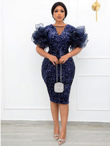 Full-length view of a woman wearing a navy blue sequined dress with puffy sleeves and silver heels.