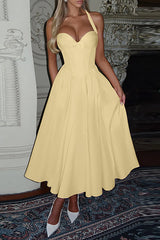 Woman in a pale yellow formal dress with a halter neckline and flowing skirt.