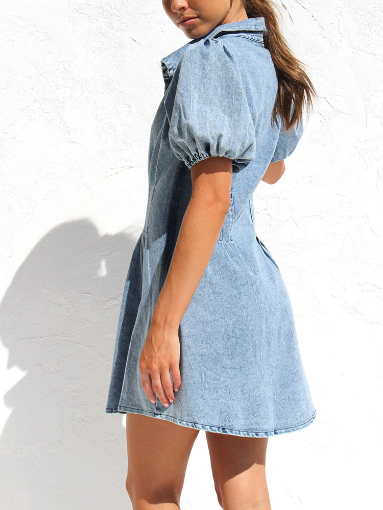Side view of a woman wearing a light blue denim shirt dress with puff sleeves.