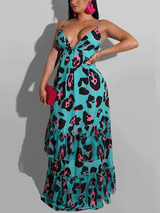 Woman wearing a turquoise maxi dress with a black and pink leopard print, featuring spaghetti straps, a plunging v-neck, and a tiered, ruffled skirt. She is holding a pink clutch and wearing large pink hoop earrings.