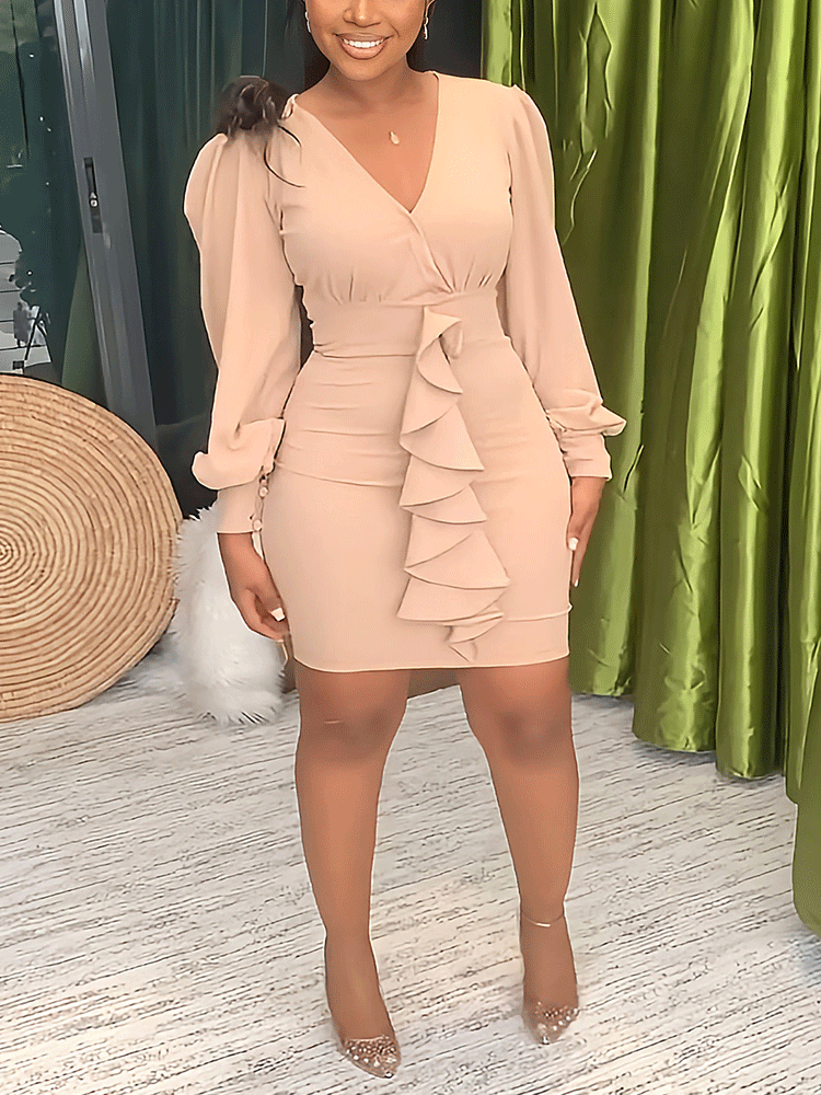 Woman wearing a beige sheath dress with long puff sleeves and ruffle detailing.