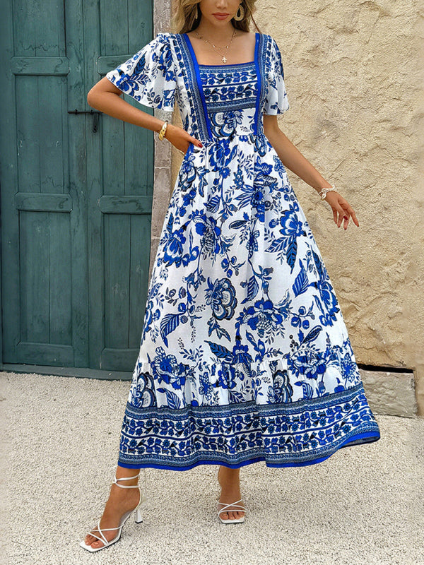 Woman wearing a blue and white floral print maxi dress with puff sleeves and a square neckline, standing outdoors.