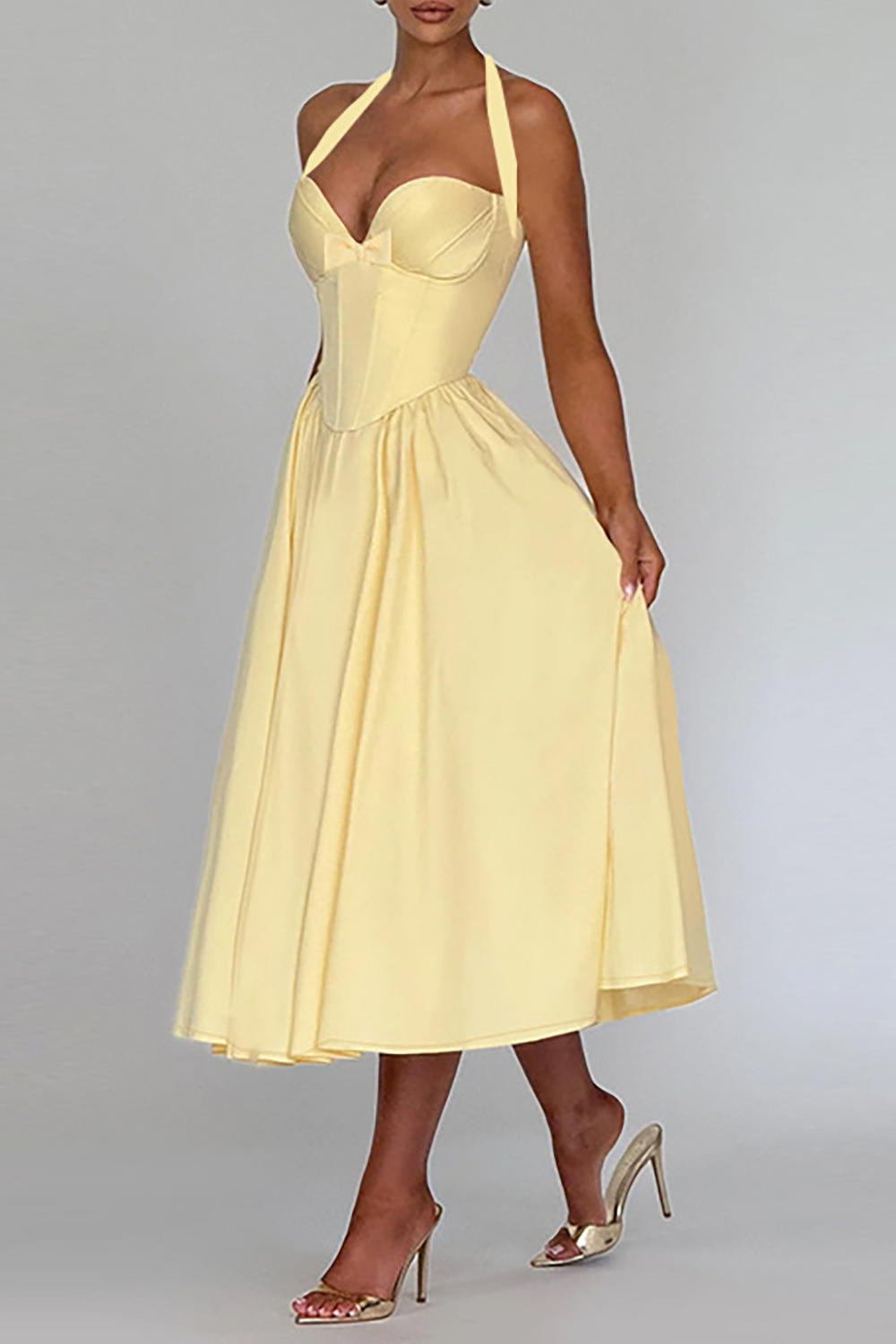 Side view of a woman in a pale yellow halter midi dress.