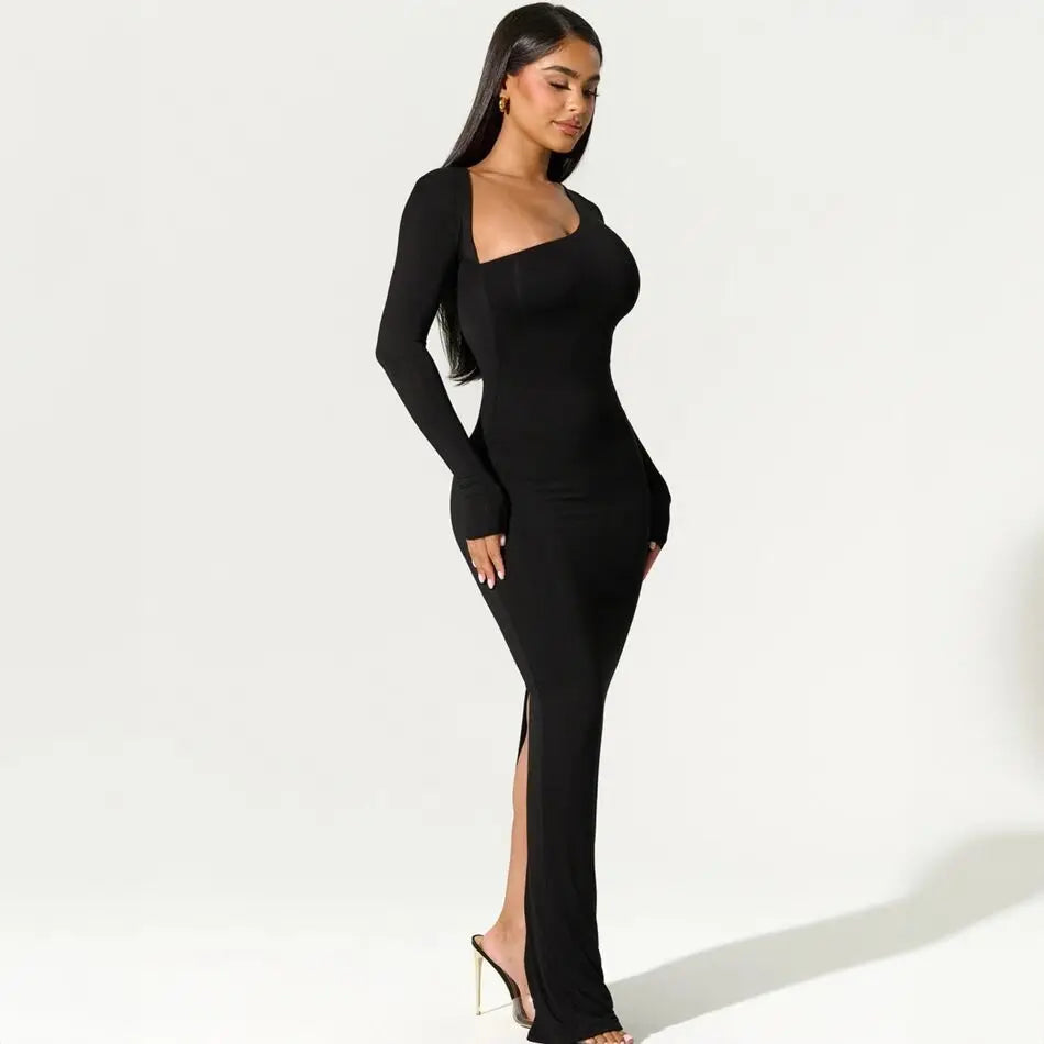 Side view of a woman in a black long-sleeved maxi dress with an asymmetrical neckline and a high slit.