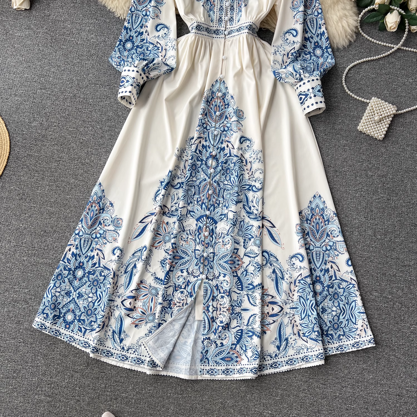 A full shot of the white maxi dress with blue paisley print, showcasing the skirt and its slit detail.