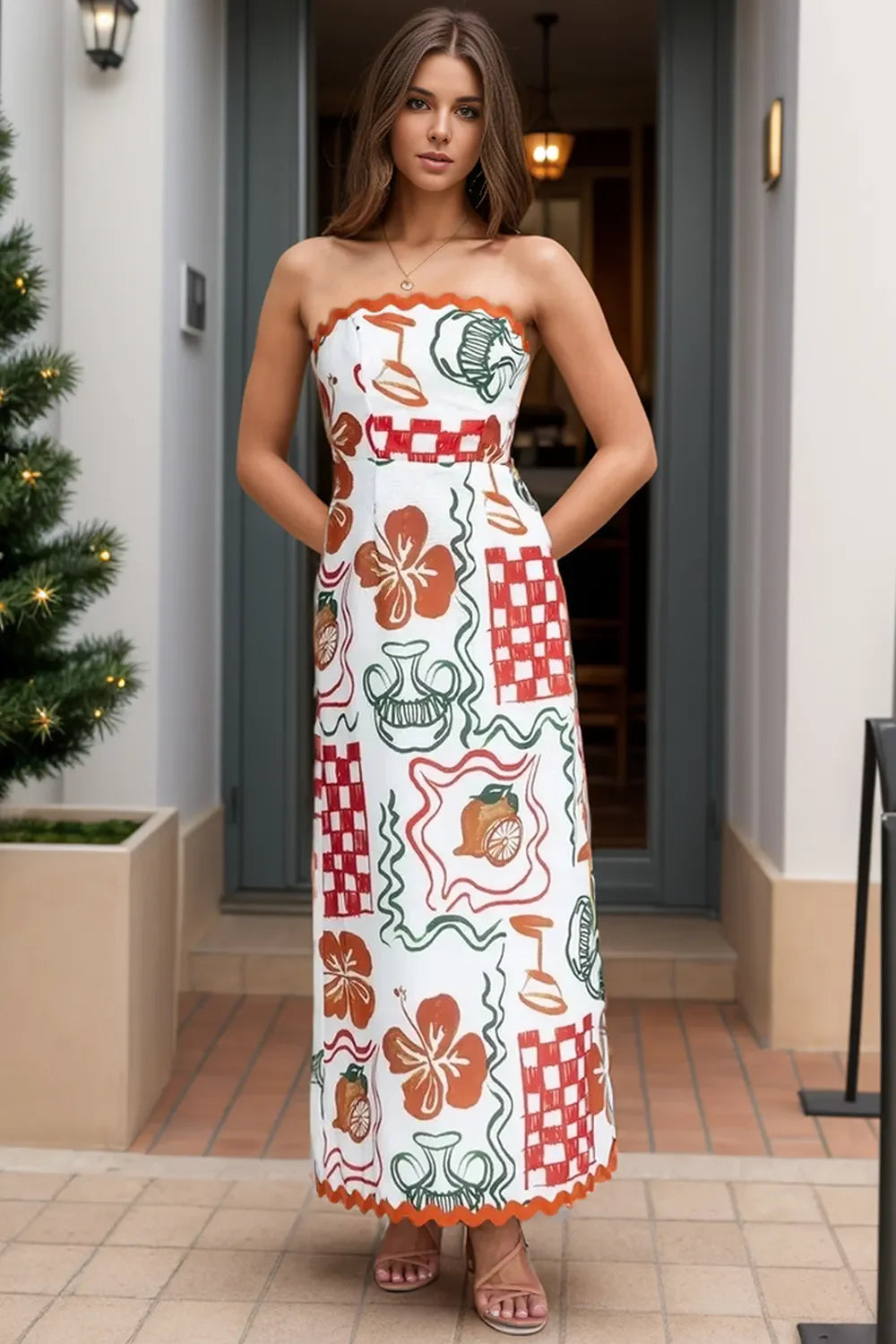 Woman wearing a white strapless maxi dress with a colorful print, standing in front of a building.