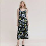 Woman wearing a black floral print midi dress with a square neckline and adjustable straps