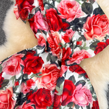 Close-up of the vibrant red and pink rose print on the fabric of the dress.