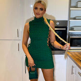 Woman wearing a green textured knit sleeveless turtleneck mini dress with lace-up sides.