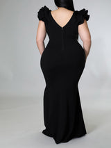 Plus-size model in an orange mermaid gown with ruffled sleeves.