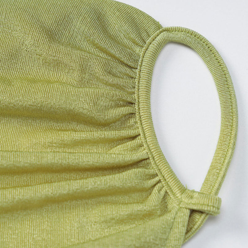Close-up of the textured fabric of a lime green mask with ruched detailing and a loop for the ear.