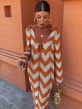 Woman wearing an orange and beige chevron knit maxi dress standing against an orange wall