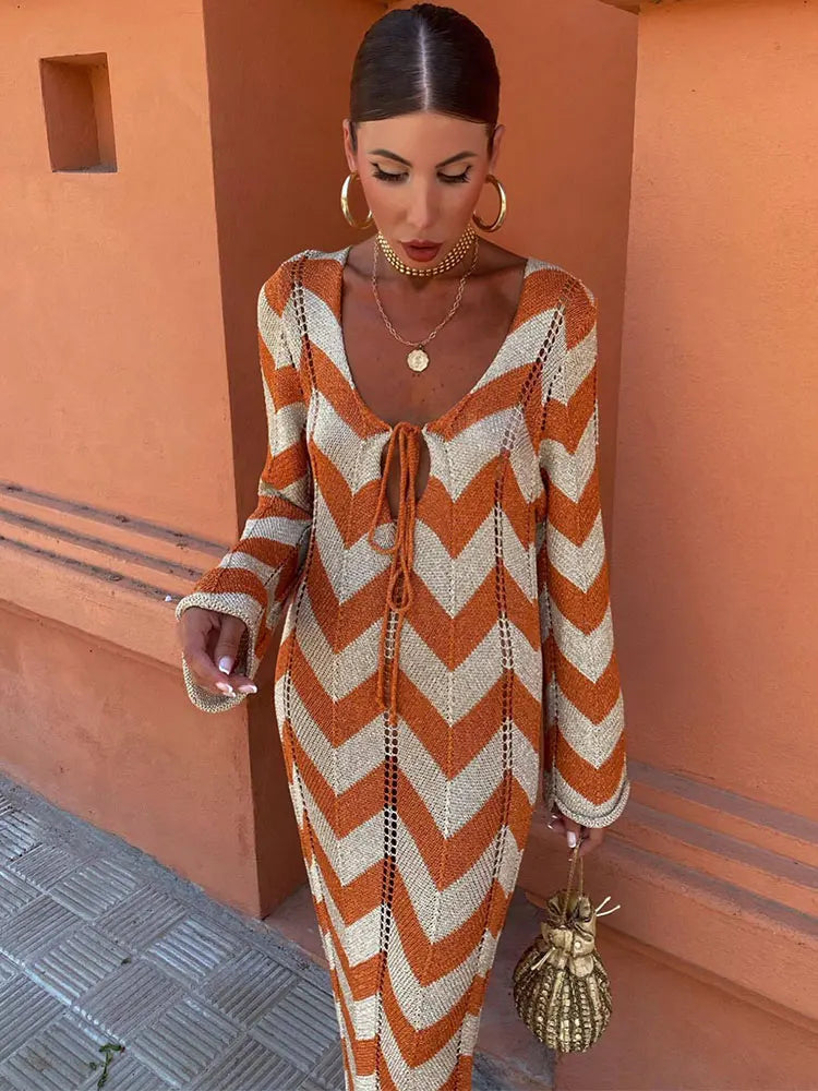 Woman wearing an orange and beige chevron knit maxi dress standing against an orange wall