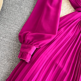 Close-up of the puff sleeve and cuff of a magenta pleated midi dress.