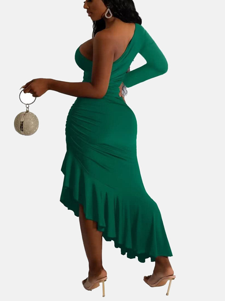 Side view of a woman in a green one-shoulder, long-sleeved maxi dress with a cut-out waist and ruffled asymmetrical hem.