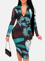 Woman in a black midi dress with a blue and brown leaf print, V-neck, long sleeves, and a belted waist.