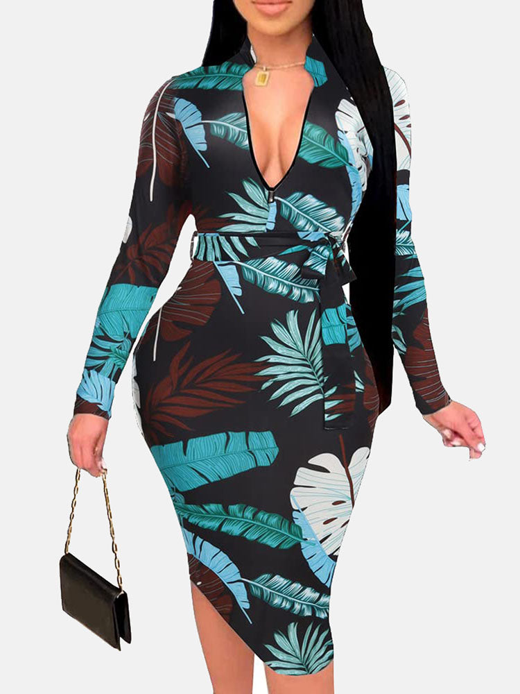 Woman in a black midi dress with a blue and brown leaf print, V-neck, long sleeves, and a belted waist.