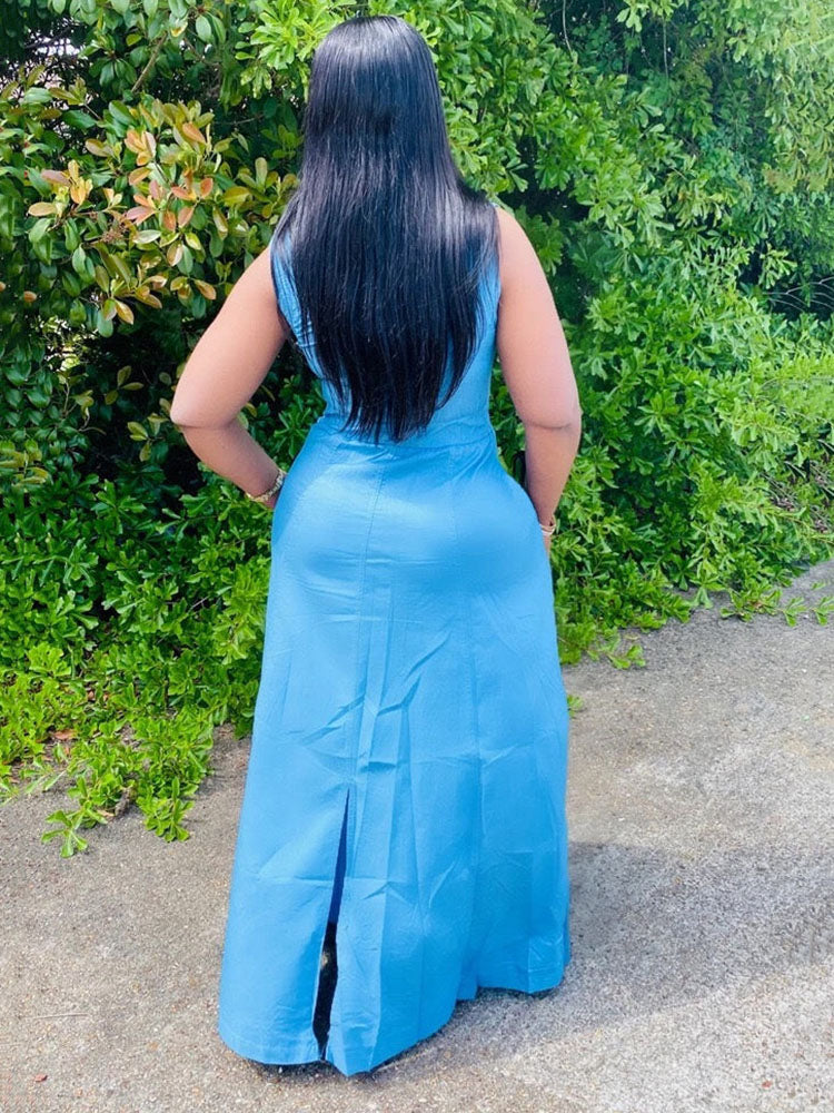 Back view of a woman in a blue denim maxi dress, highlighting the length and hem slit.