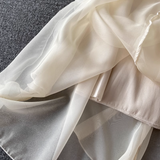 Close-up of the layered chiffon fabric of a cream-colored dress, showing the sheer overlay and satin lining.