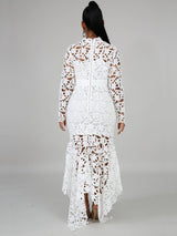 Back view of a woman wearing a white long-sleeved lace mermaid dress with a high neckline and a sash.