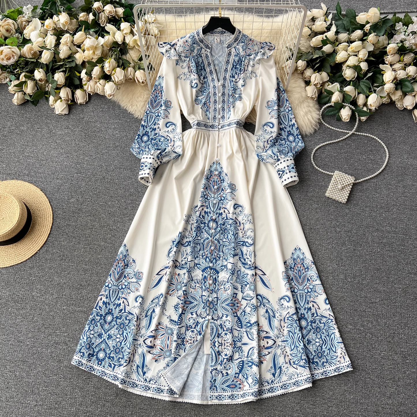 A flat lay of the white maxi dress with blue paisley print, styled with decorative elements for a visually appealing presentation.
